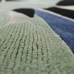 Close-up of a textured green rug with geometric patterns.