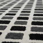 Close-up of a geometric patterned rug with black and gray squares.