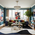 Modern living room with a chandelier, colorful artwork, an abstract wool rug, and a green sofa.