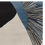 Close-up view of a contemporary area rug featuring an abstract design with black, blue, and cream tones. This hand-tufted wool rug is perfect for adding a modern touch to living room spaces, especially in an 8x10 size.