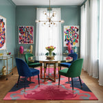 Dining room with colorful chairs, table, and abstract art on a pink rug.