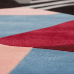 Close-up of a colorful geometric-patterned rug with red, blue, and pink sections.