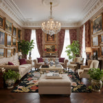 Luxurious living room with ornate decor, including a chandelier, framed paintings, and elegant furniture.
