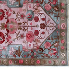 Top view of a Garden Enchantment Knotted Wool Rug featuring a vibrant floral design. The area rug showcases intricate patterns with pink and red flowers on a soft pastel background, ideal for enhancing living room decor.