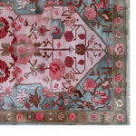 Top view of a Garden Enchantment Knotted Wool Rug featuring a vibrant floral design. The area rug showcases intricate patterns with pink and red flowers on a soft pastel background, ideal for enhancing living room decor.