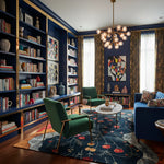 Modern living room with bookshelves, a floral wool rug, green armchair, and blue sofa.