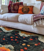 A beautifully detailed Garden Gate Tapestry Hand Tufted Area Rug with vibrant floral patterns in red and orange, adding a touch of elegance to the living room. The wool rug complements the cozy white sofa adorned with colorful, patterned cushions, perfect for both living room and dining room settings.