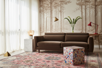 Modern living room with a brown sofa, colorful rug, and forest-themed wallpaper.