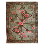 This beautiful area rug, titled 'Garden of Serein Knotted Wool Rug', features an intricate floral design with vibrant pink blossoms on a soft green background. Its elegant pattern makes it ideal for adding a touch of luxury to any living room. Perfect as a wool rug or as part of your collection of area rugs for living room, this piece effortlessly enhances the ambiance of your space.