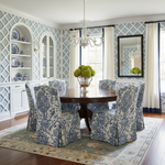 Dining room with patterned chairs and a chandelier, knotted blue rug