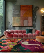 Elegant living room featuring a vibrant wool area rug with a colorful abstract design, perfect for enhancing bedroom or living room decor. The rug adds a pop of color beneath a plush pink sofa and modern art piece, creating a cozy and stylish atmosphere.