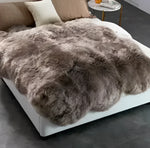 Luxurious Genuine Sheepskin Wool Area Rug draped over a modern bed, showcasing its plush texture and rich, natural tones. Perfect for enhancing comfort and style in your living room area rugs collection.