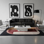 Modern living room with black sofa, abstract art, and geometric rug.