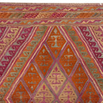 A vibrant Gilded Citrus Diamonds Hand Knotted Area Rug featuring an intricate geometric pattern in shades of orange, pink, and green. Perfect for adding a splash of color to your living room, this 8x10 rug combines traditional craftsmanship with modern design.