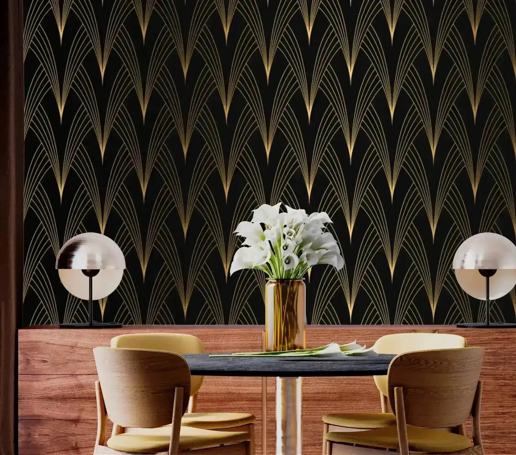 Gilded Grandeur Art Deco wallpaper in dining nook; gold fan pattern, dark table with wood chairs, white calla lilies in gold vase