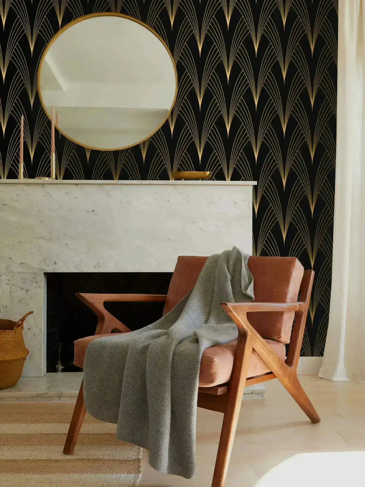Gilded Grandeur wallpaper behind marble fireplace; round gold mirror above mantel, terracotta leather armchair with grey throw