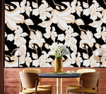 Gilded Petal wallpaper behind dark dining table with yellow chairs and gold vases; white gold-lined petals on black
