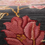 Close-up of a floral patterned rug with pink and red flowers on a dark background.