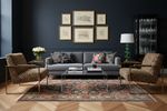Living room with dark blue walls, gray sofa, and patterned rug.