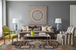 Living room with gray walls, colorful mandala painting, and patterned rug.