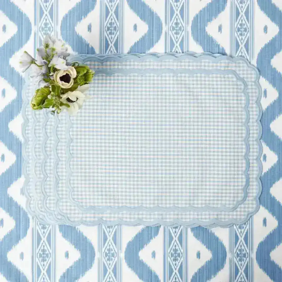pale blue gingham placemat with scalloped edge, flat lay on ikat tablecloth with white anemone flower accent
