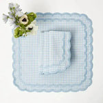 pale blue gingham scalloped-edge placemat square with matching napkin and white anemone bouquet, overhead