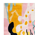 A vibrant Golden Abstract Reef Dance hand-tufted area rug, showcasing a contemporary design with splashes of yellow, pink, blue, and black. This wool rug is perfect for adding a touch of modern art to your living room.