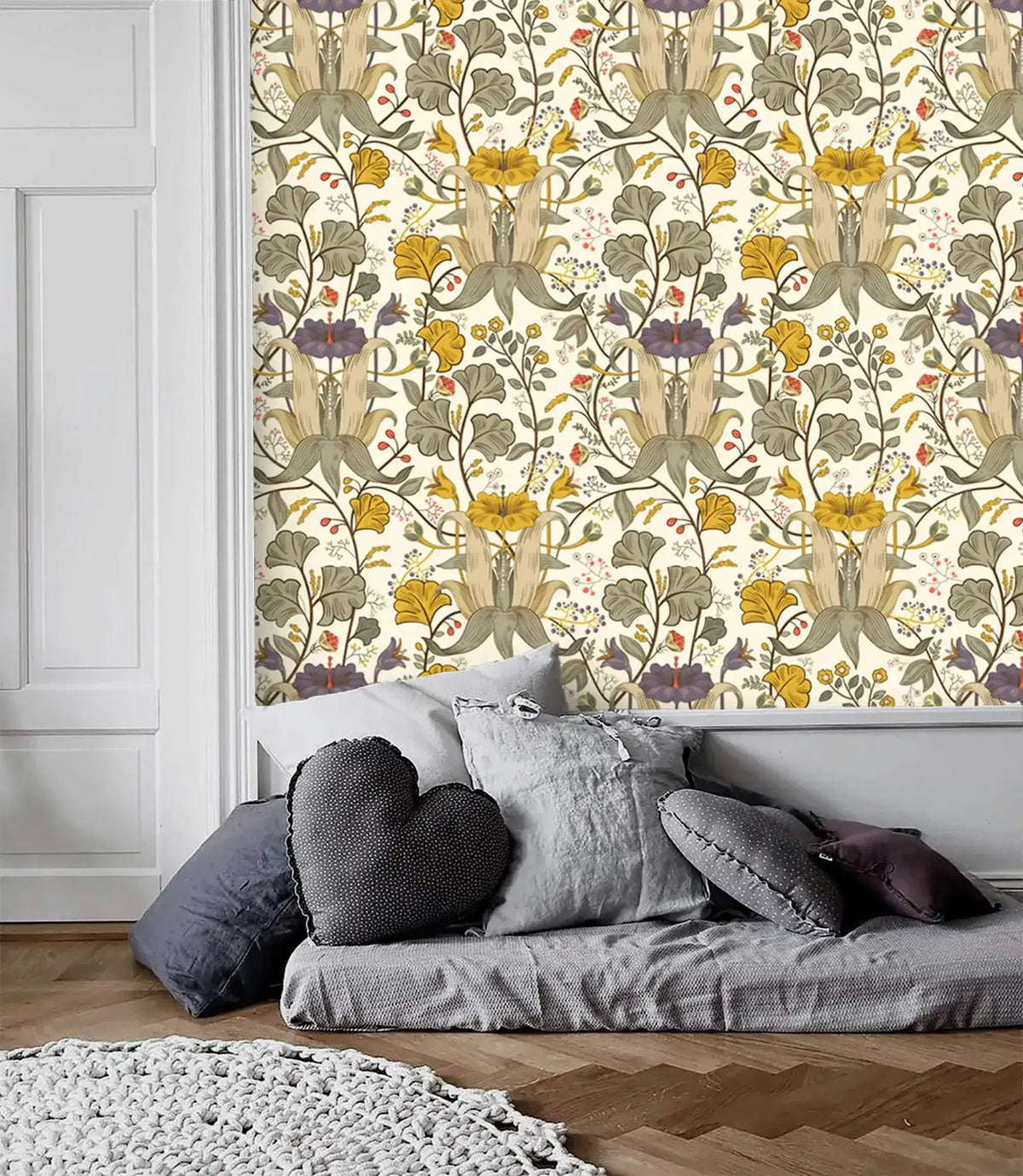 Vintage floral wallpaper with golden blooms and sage green botanicals as accent panel above a gray low sofa with pillows