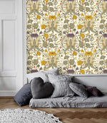Vintage floral wallpaper with golden blooms and sage green botanicals as accent panel above a gray low sofa with pillows