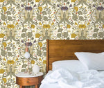 Vintage yellow floral wallpaper with sage and purple blooms behind a dark wood bed with white pillows and round nightstand