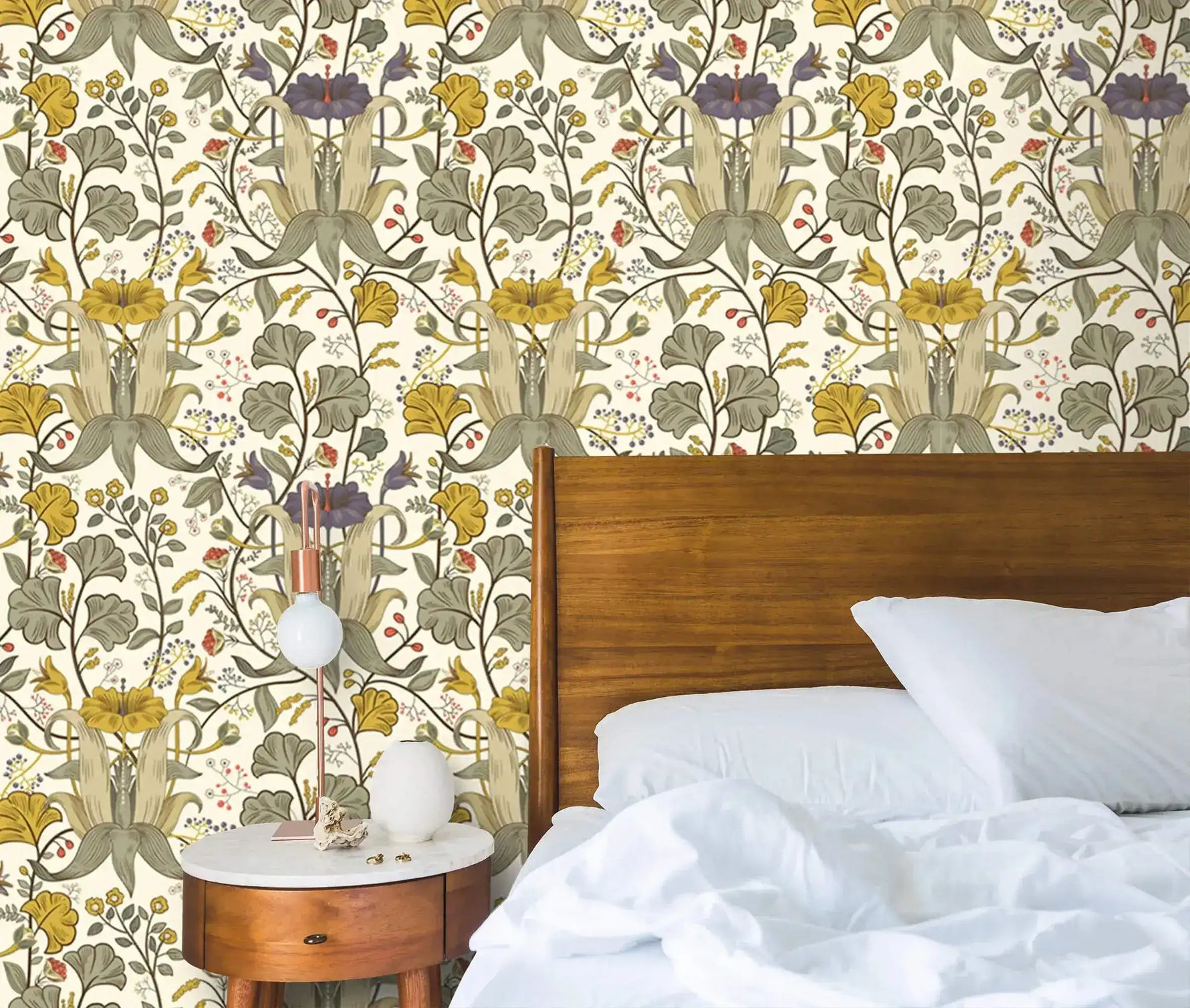Vintage yellow floral wallpaper with sage and purple blooms behind a dark wood bed with white pillows and round nightstand