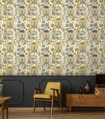 Vintage golden blooms floral wallpaper on cream with purple accents above dark wainscoting, mustard chair nearby