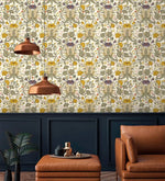 Vintage golden blooms wallpaper above dark navy wainscoting with copper pendant lights and tan leather armchair