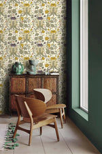 Vintage yellow floral wallpaper beside a sage green wall, with a carved cabinet, green vases, and wood lounge chair