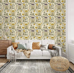 Vintage yellow floral wallpaper with green and purple botanicals on cream behind a white tufted sofa and rattan pouf
