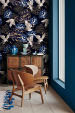 Golden crane flight wallpaper by a window with carved cabinet, white cranes among blue peonies on navy