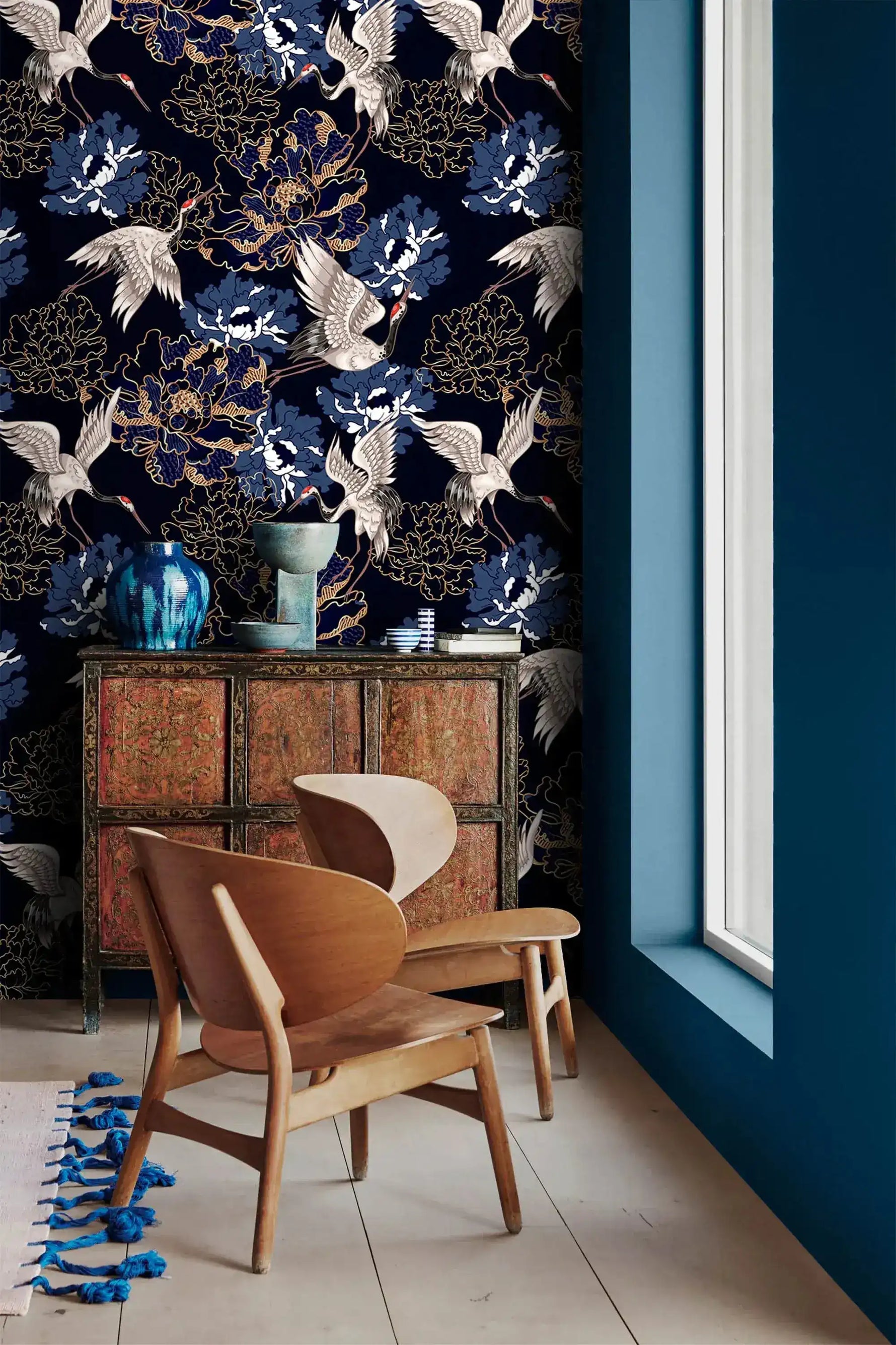 Golden crane flight wallpaper by a window with carved cabinet, white cranes among blue peonies on navy