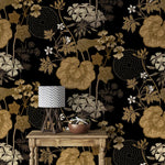 Console table with lamp against golden creeper vine wallpaper, gold blooms on black