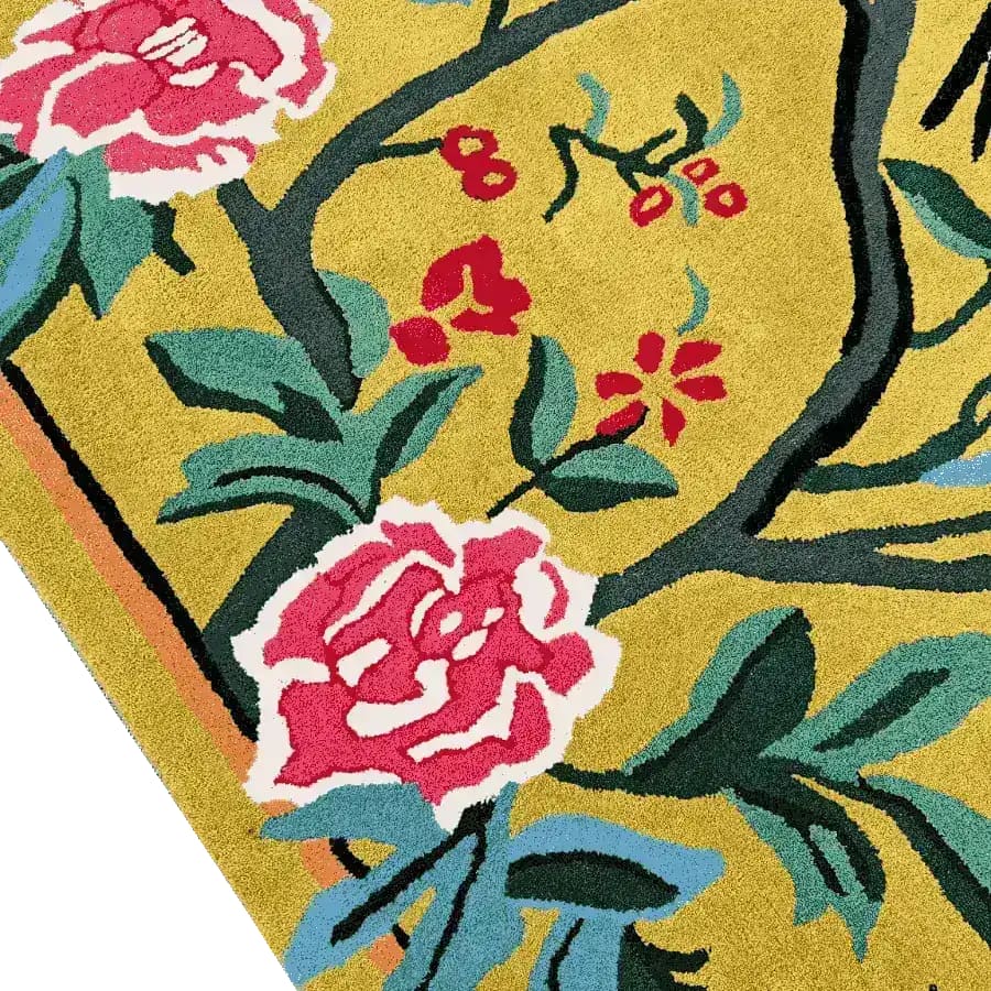 Close-up of the Golden Garden Hand Tufted Rug, showcasing a vibrant floral pattern with pink and red flowers against a rich yellow background. Perfect for adding a touch of elegance to dining room or living room area rugs.