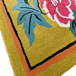 Close-up of the Golden Garden Hand Tufted Area Rug, showcasing a vibrant floral design with bold pink flowers and blue leaves on a warm yellow background. Perfect for adding a splash of color to your dining room or living room area, this wool rug offers a cozy yet stylish touch.