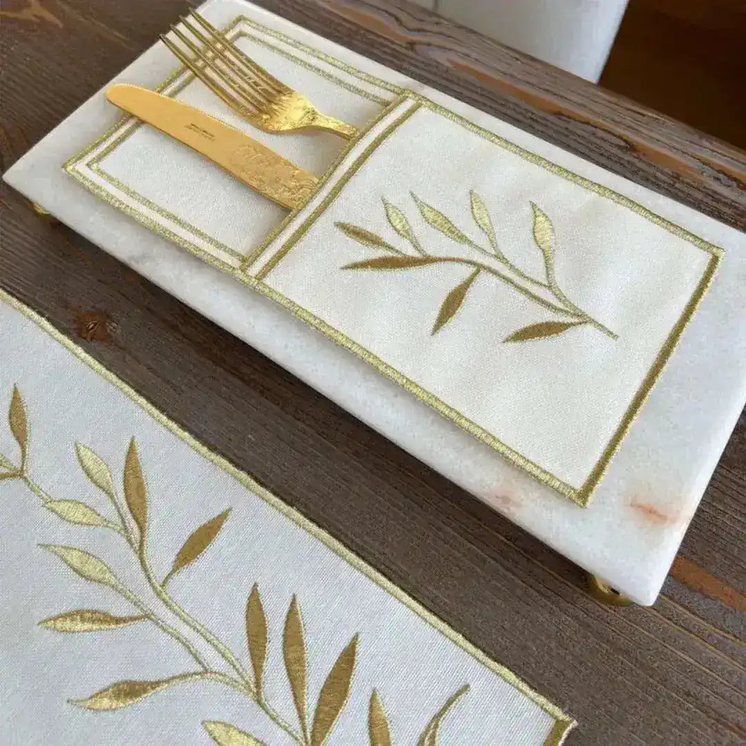 Golden Leaf Elegance placemat detail showing white linen with gold embroidered leaf spray in gold-stitched rectangle border