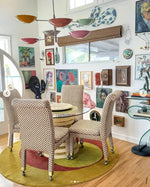 Stylish living room featuring a Golden Orange Geometry Round Hand Knotted Wool Rug, providing a warm and inviting atmosphere. The rug's abstract design complements the eclectic decor, including patterned chairs and vibrant wall art. Perfect for bedroom rugs or area rugs for living room, this wool rug adds a cozy touch to any space.