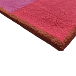 Close-up view of the Golden Trim Minimalist Geometric Hand Tufted Area Rug in pink, highlighting the plush wool texture and vibrant colors. Perfect as a living room rug in 8x10 size, this vintage-inspired piece adds a modern touch to your decor.