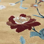 Close-up of a floral patterned rug with red flowers and green leaves on a beige background.