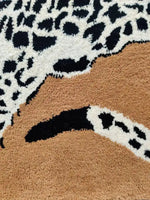 Close-up view of the Goldy Leopard Hand Tufted Wool Rug, showcasing its intricate leopard print design in black and white, with warm brown accents. This area rug is perfect for adding a stylish touch to large living rooms, enhancing the decor with its luxurious wool texture.