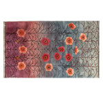 The Gossamer Dawn Knotted Wool Rug features a stunning floral design with red and orange blossoms set against a gradient backdrop of blue and pink. This elegant area rug adds a touch of sophistication to living room spaces, perfect for those seeking quality wool rugs and stylish living room area rugs.