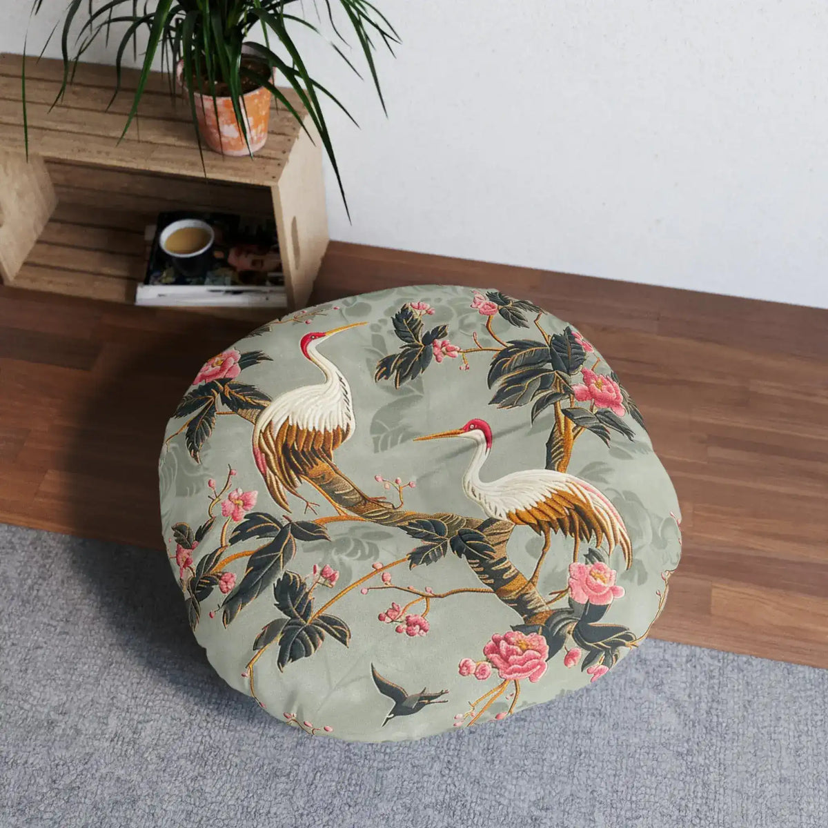 Graceful Crane and Blossom Pattern Floor Pillow styled in living space on hardwood floor beside wood crate shelf and plant