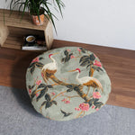 Graceful Crane and Blossom Pattern Floor Pillow styled in living space on hardwood floor beside wood crate shelf and plant