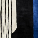 Top view of the Graphic Stripe Dream Hand Tufted Area Rug, showcasing its bold contemporary design with black and white stripes alongside a striking blue section. Perfect for large living room spaces, this 8x10 wool rug adds a modern touch to any decor.