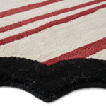 Close-up of a striped rug with red, white, and black colors.